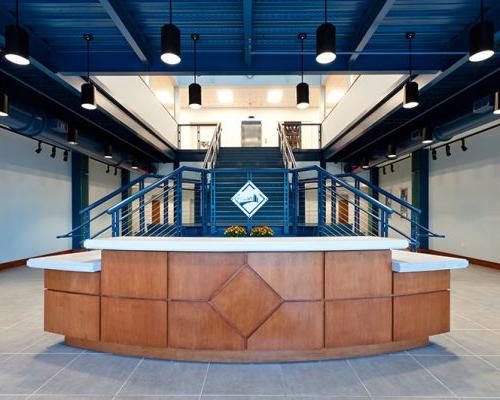 Wood paneled reception desk in front of bifurcated blue stairway