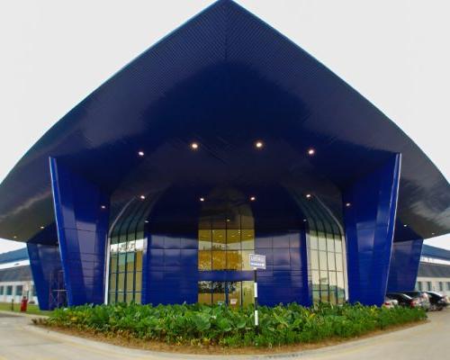 Exterior entrance of Spirit AeroSystems SE Asia. Bright blue triangular building.